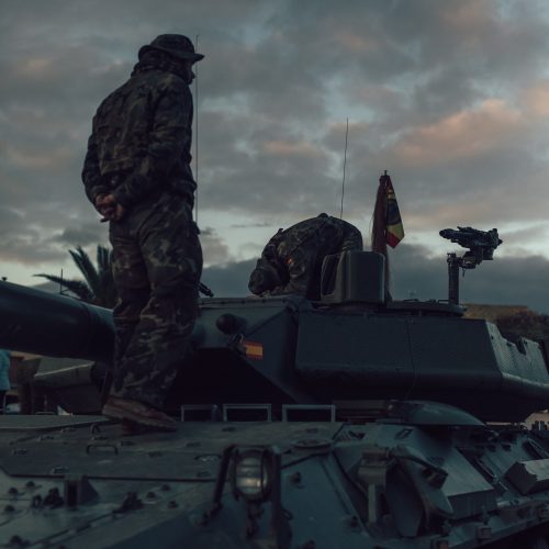 Militares españoles sobre un carro de combate Leopard en maniobras al atardecer.