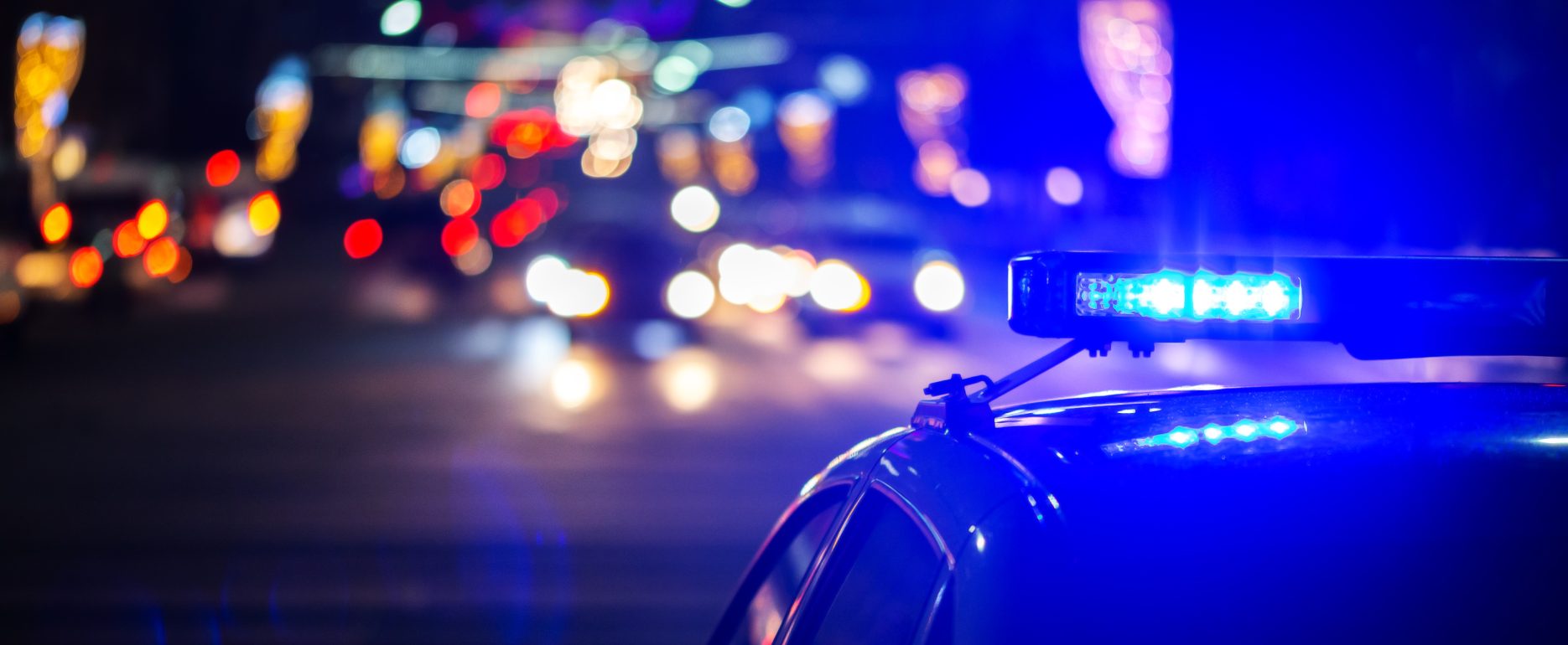 Coche de policía con luces de emergencia encendidas durante una intervención nocturna en la ciudad.