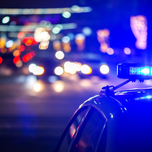 Coche de policía con luces de emergencia encendidas durante una intervención nocturna en la ciudad.