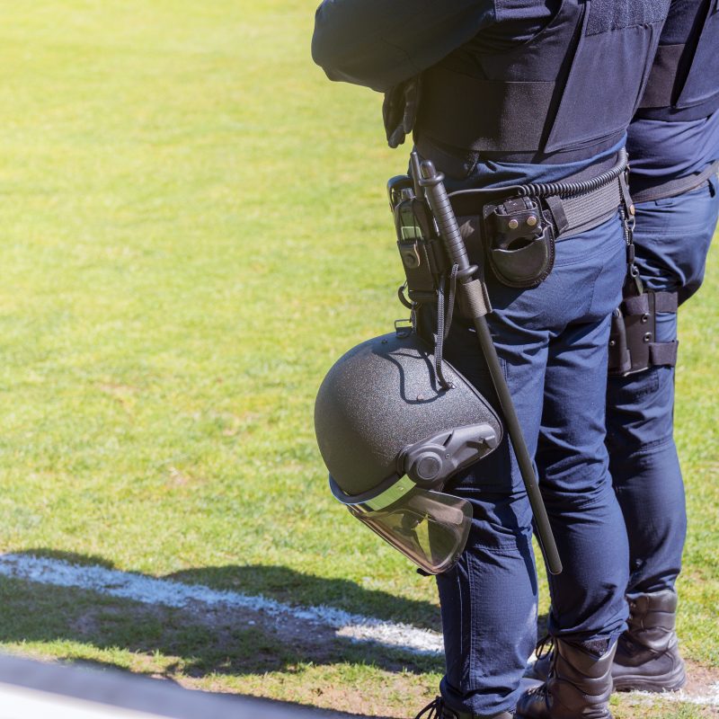 Agentes antidisturbios con uniforme de protección y casco en la mano durante un operativo en un estadio.