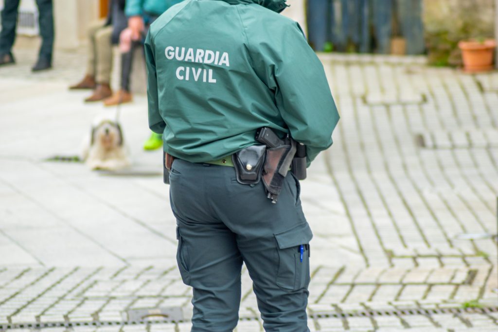 Agente de la Guardia Civil patrullando en una calle, con uniforme oficial y arma reglamentaria.